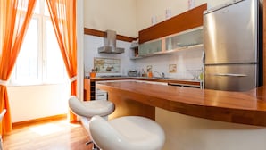A modern kitchen with a stainless steel refrigerator, wooden countertop, and two white bar stools. - Residenza Duomo 314 (Naples)