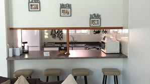 A modern kitchen with a bar area, bar stools, and a seating area with a sofa and cushions. - Low Tide (St. Lucia)