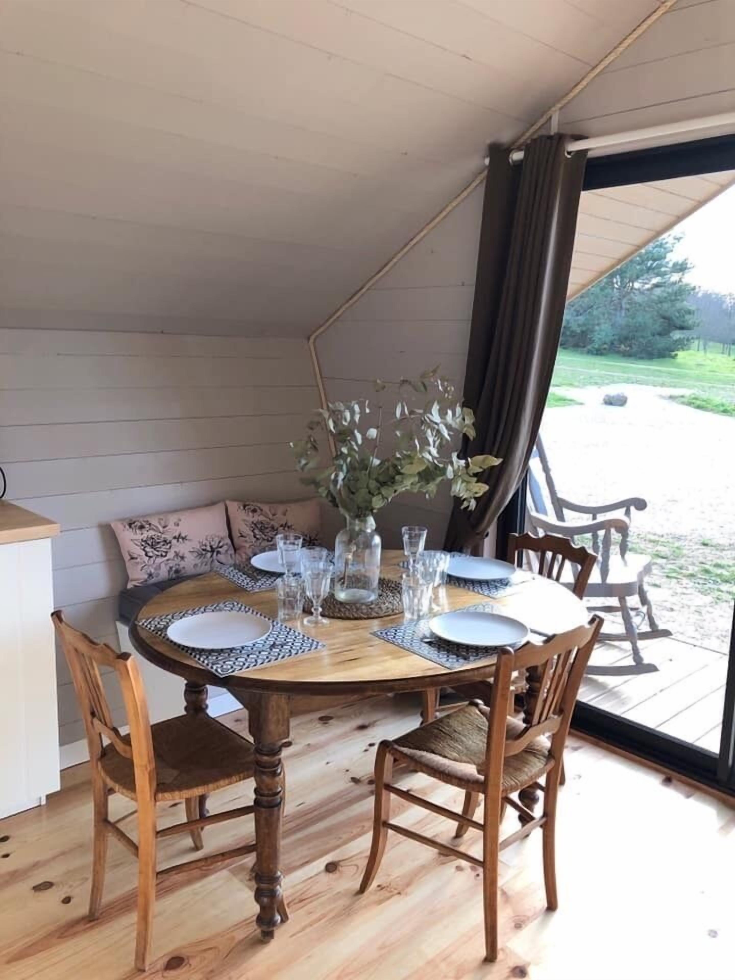 Et rundt træbord med seks stole, en vase med blomster og glas.