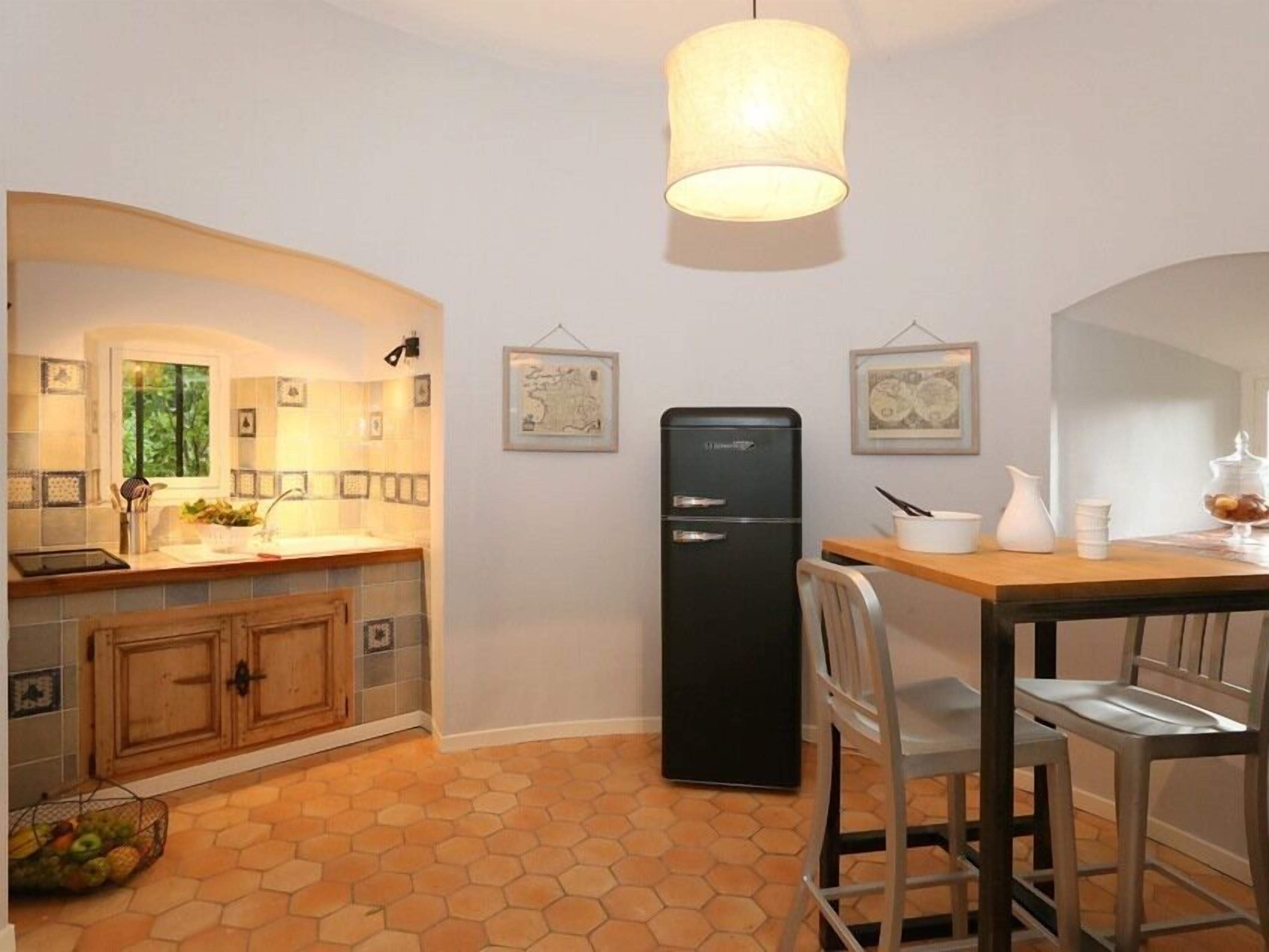 Una cocina compacta con un mueble de madera, un refrigerador negro y una mesa de comedor con sillas.
