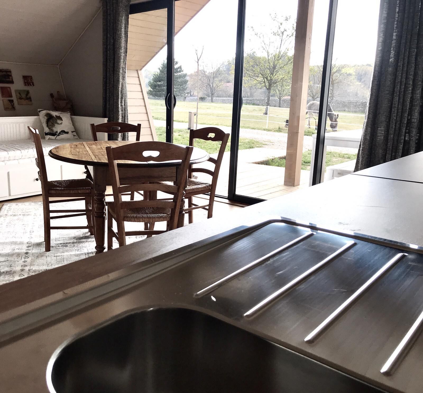 Een moderne keuken met een roestvrijstalen spoelbak, een houten eettafel en stoelen.