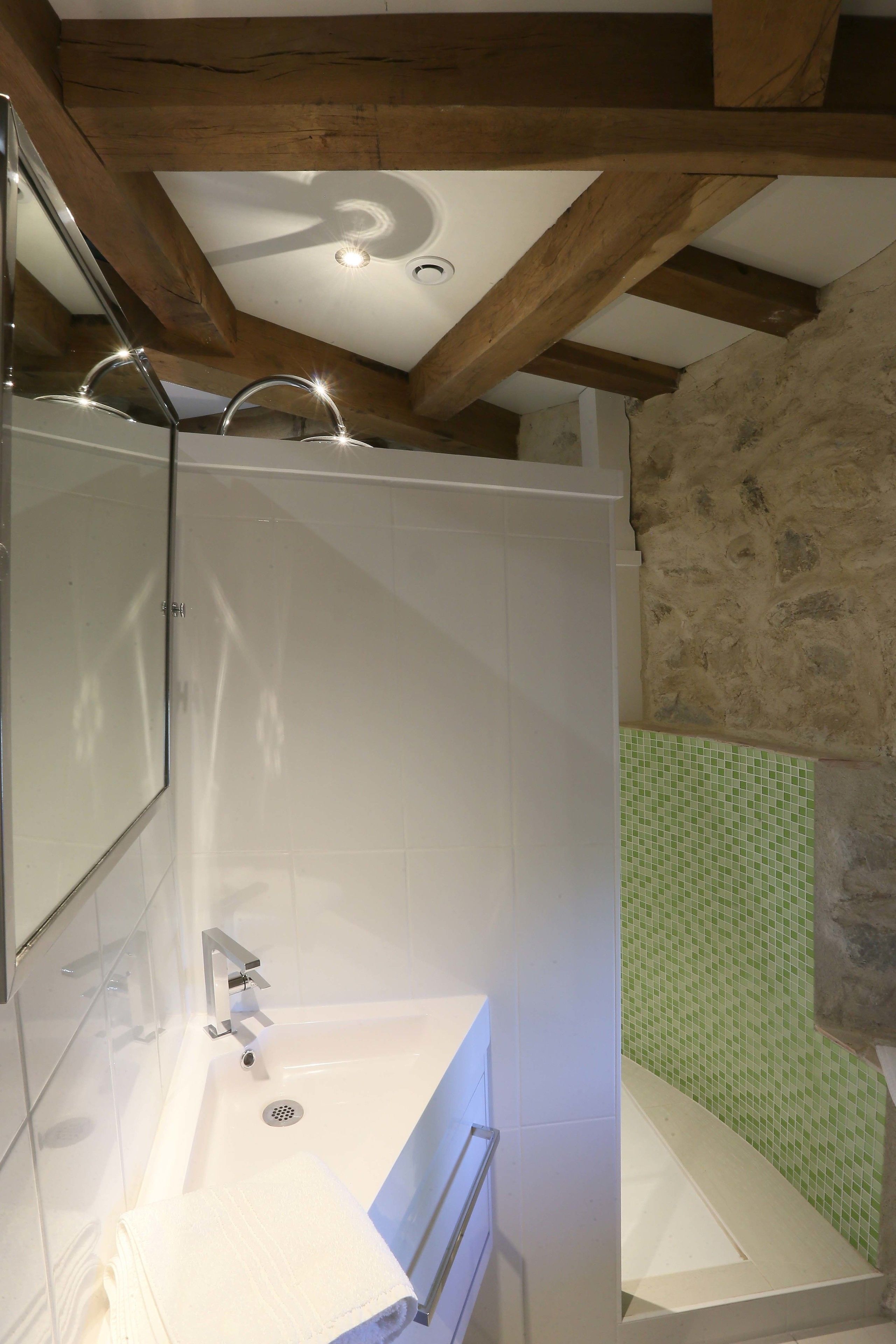 A bathroom with a white sink, mirror, and shower area.