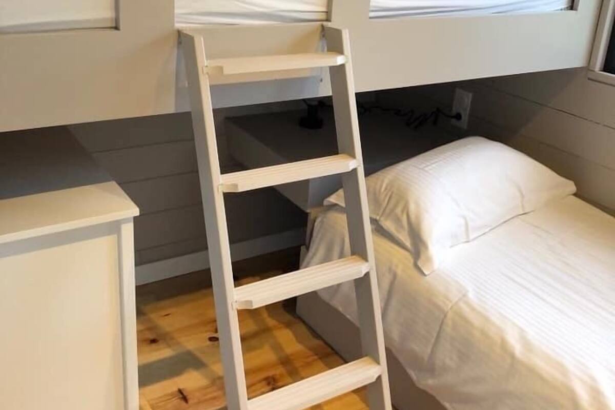 Habitaci ó amb un llit superposat, una escala de fusta, una tauleta de nit i una finestra.