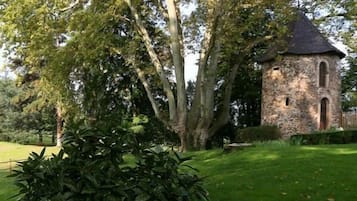 Una torre de piedra con techo cónico, rodeada de abundante vegetación y árboles.