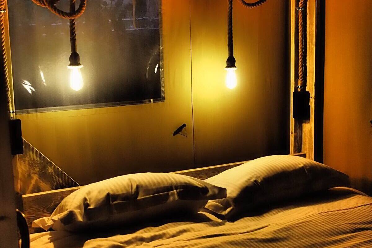 Un llit amb capçalera, dues làmpades de nit i una finestra amb vistes.