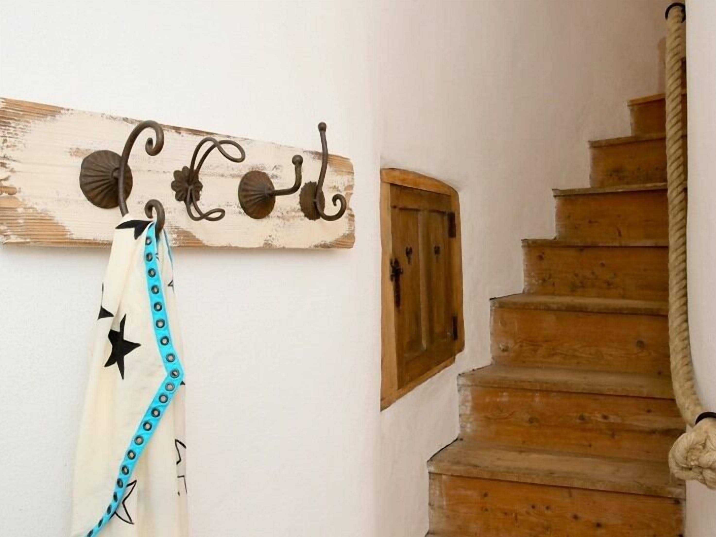 A wooden staircase with a rope handrail, a rustic wall-mounted decoration, and a towel hanging on the wall.