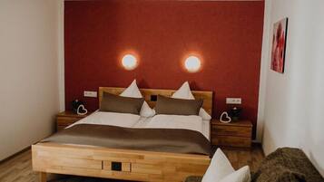 A bedroom with a wooden bed, two bedside tables, and a red accent wall.