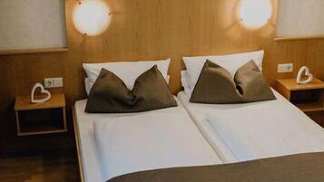 A double bed with a wooden headboard, two bedside tables with lamps, and a wall-mounted artwork above the bed.