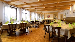 Un restaurant avec des poutres en bois, des tables ornées de serviettes vertes et un sol décoré d’un motif en chevrons.