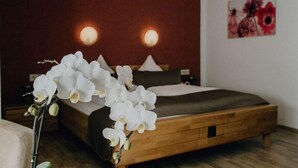 Une chambre à coucher avec un lit en bois, du linge de lit blanc et un luminaire fixé au mur.