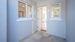 Ein Flur mit einer zur Schlafzimmertür führenden Öffnung, der Zimmernummer 3 an der Wand und einem Fenster mit Jalousien.