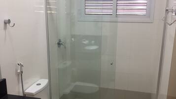 Un baño moderno con cabina de ducha de vidrio, inodoro blanco y lavamanos negro.