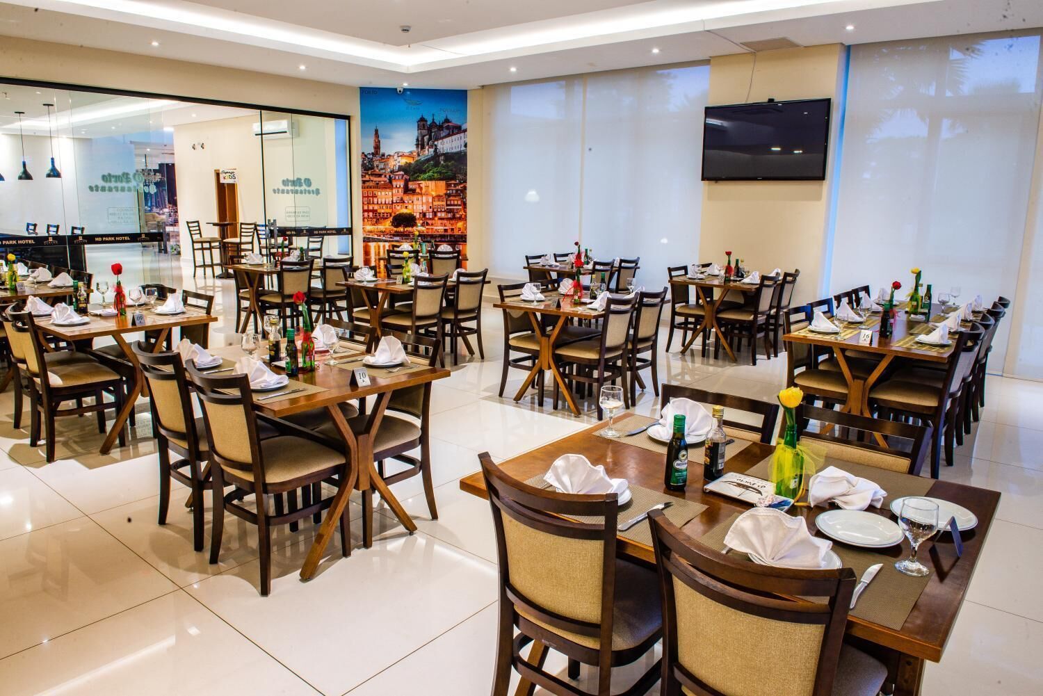 A spacious dining area with multiple tables and chairs, a large window with a cityscape view, and a sign for the Park Hotel.