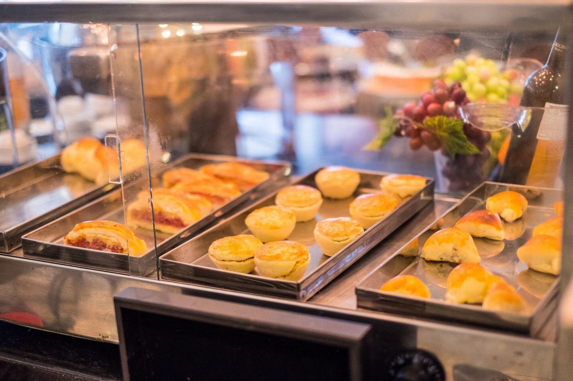 A buffet with various baked goods, including muffins and rolls, displayed in trays.