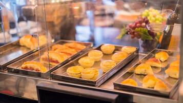 A buffet with various baked goods, including muffins and rolls, displayed in trays.