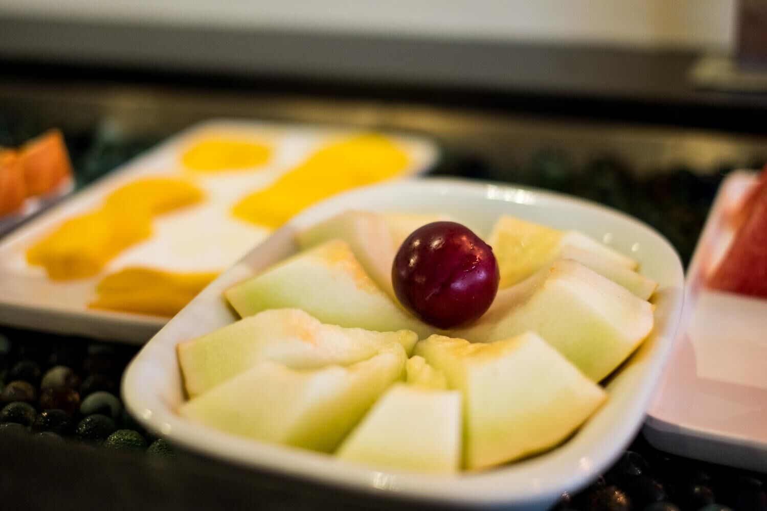 Un plato de fruta cortada con una cereza encima.