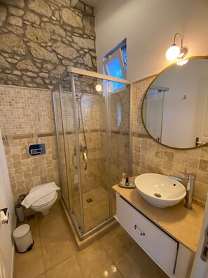 A bathroom with a glass-enclosed shower, a white sink, and a mirror with a gold frame. - Selin Hotel (Cesme)