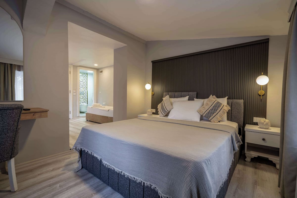 Quarto moderno com uma cama grande, mesas de cabeceira e uma escrivaninha.