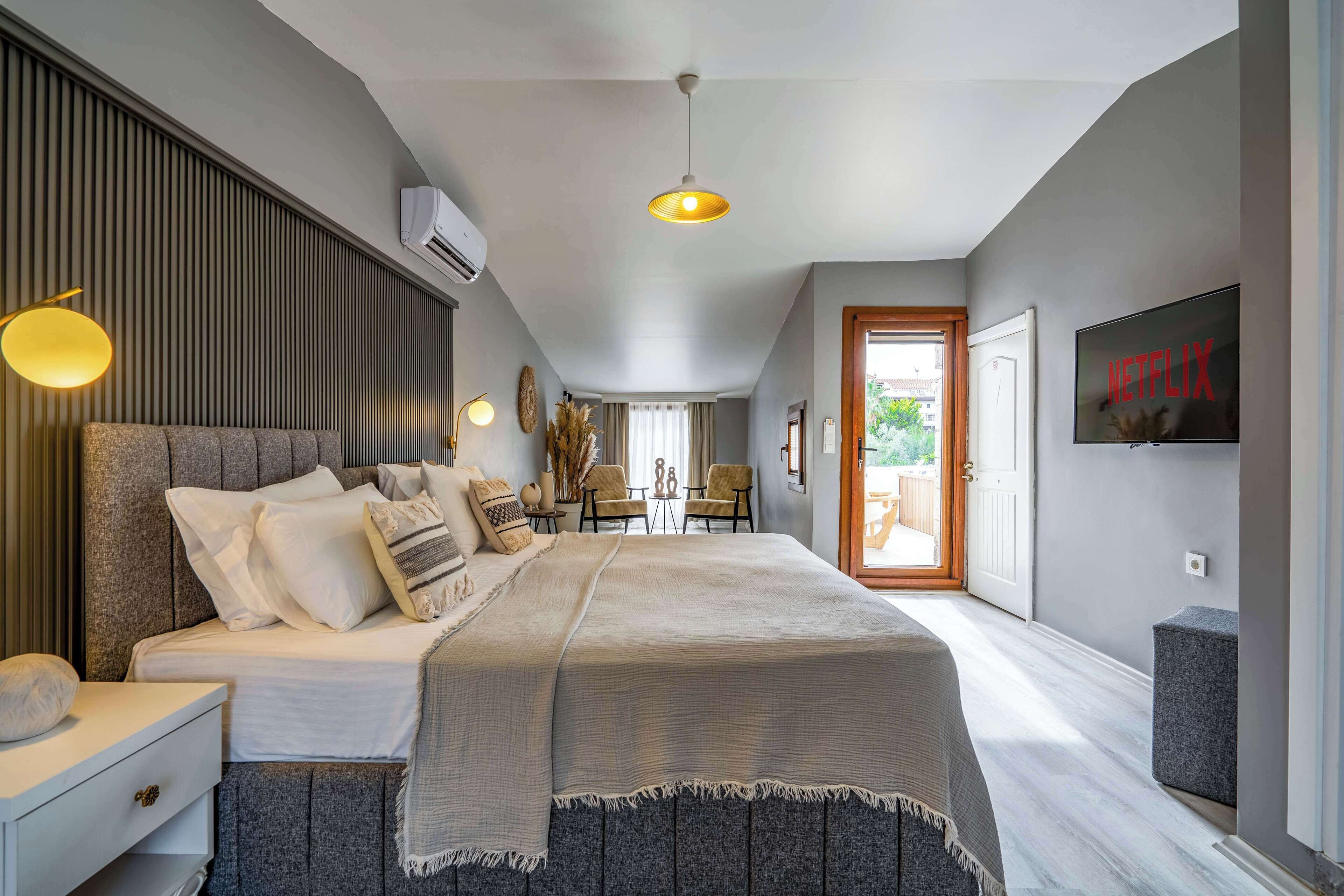 Ein modernes Schlafzimmer mit einem großen Bett, Nachttischen, einem Fernseher und Blick ins Freie.