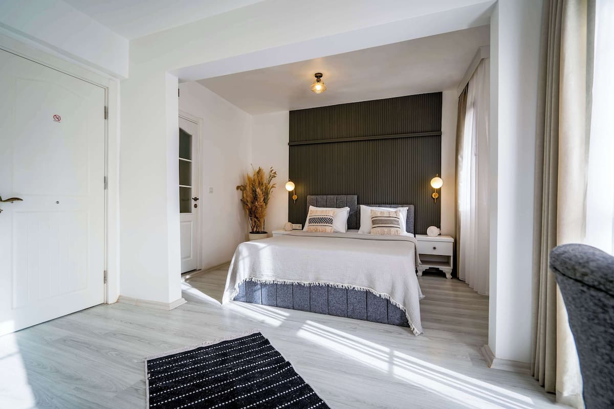 Um quarto moderno com uma cama grande, abajures e vista para o corredor.