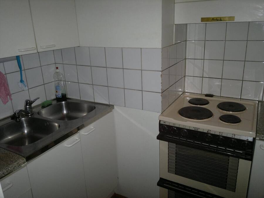 A kitchen with white cabinets, a double sink, and a stove.