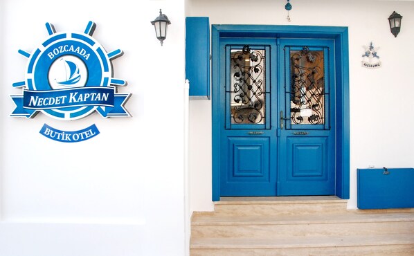 Una puerta azul con paneles de vidrio decorativos y un letrero con el logotipo de un velero.