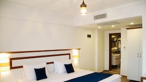 A hotel room with a large bed, bedside tables, a wardrobe, and a bathroom visible through an open door. - Necdet Kaptan Bozcaada (Bozcaada)