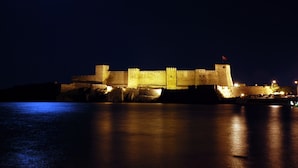 A large, illuminated castle-like structure with a moat, likely a historic fortification. - Necdet Kaptan Bozcaada (Bozcaada)