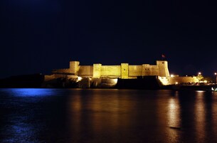 A large, illuminated castle-like structure with a moat, likely a historic fortification.