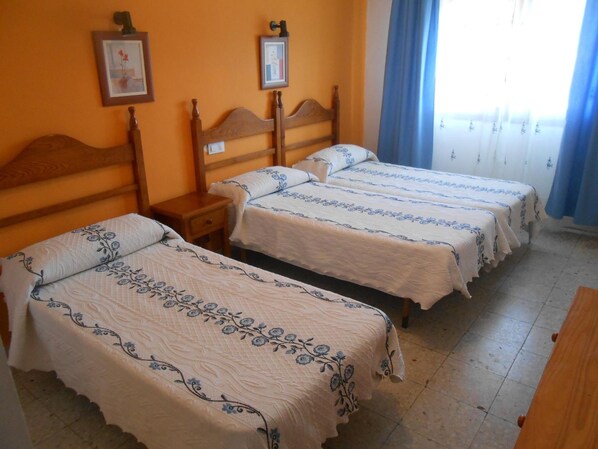 Habitación de hotel con dos camas individuales, cabeceros de madera y una mesita de noche de madera.