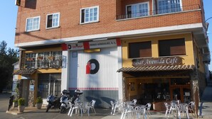 Un edificio de varios pisos con un cartel que dice "Hostal Avenida".