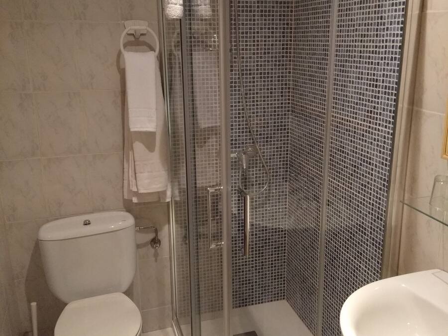 A bathroom with a glass-enclosed shower, a toilet, and a sink.