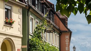 Un hotel con un cartel llamativo que dice 'HOTEL', un balcón con plantas colgantes y una bicicleta estacionada al frente.
