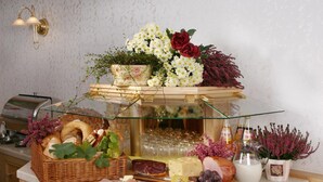 Montaje de bufé con diversos alimentos, como pan, queso y carnes, junto con una selección de flores y una vitrina de cristal.