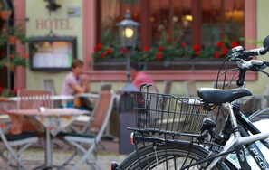 A bicycle with a basket attached to the back, parked in front of a building with a sign that reads "HOTEL". - Hotel Rose (Volkach)
