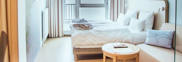 Une chambre d’hôtel avec un lit, une table ronde en bois et un canapé.