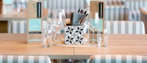 A dining table set with glasses, cutlery, and menus in a restaurant with striped chairs.