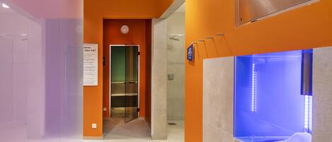 A modern bathroom with a glass shower enclosure, a visible sign with text, and a ceiling with recessed lighting.