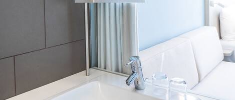 A modern bathroom with a white sink, a mirror, and a towel rack.