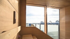 A modern interior with a wooden bench and large windows overlooking a waterfront. - aja Travemuende (Lübeck)