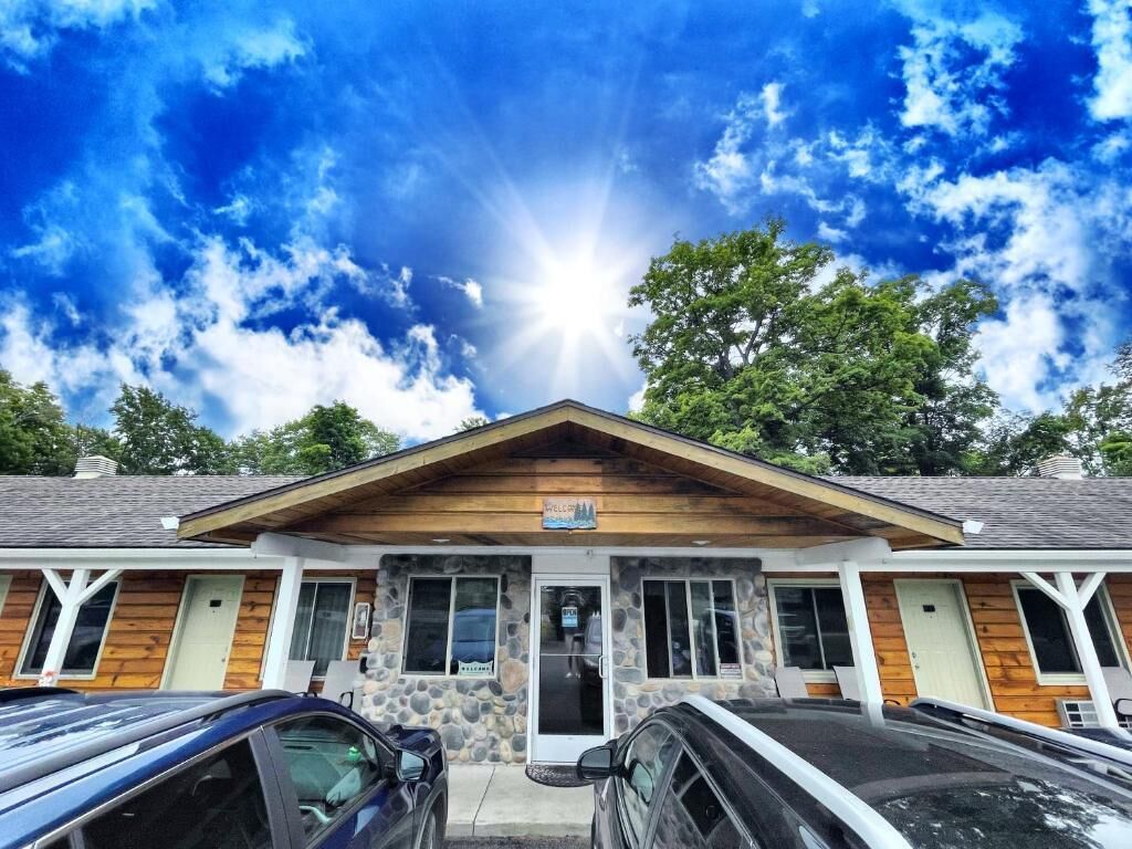 A building with a stone facade, a wooden front porch, and a clear sky with sunlight.