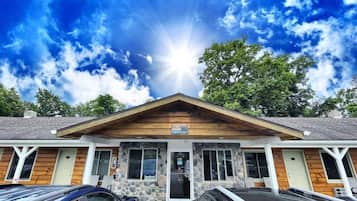 A building with a stone facade, a wooden front porch, and a clear sky with sunlight.