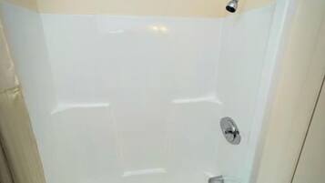 A walk-in shower with a glass door, a showerhead, and a towel rack.