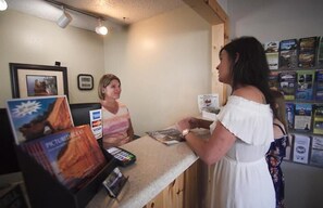 A reception area with a counter, a framed picture on the wall, and informational brochures. - Alger Falls Motel (Munising)