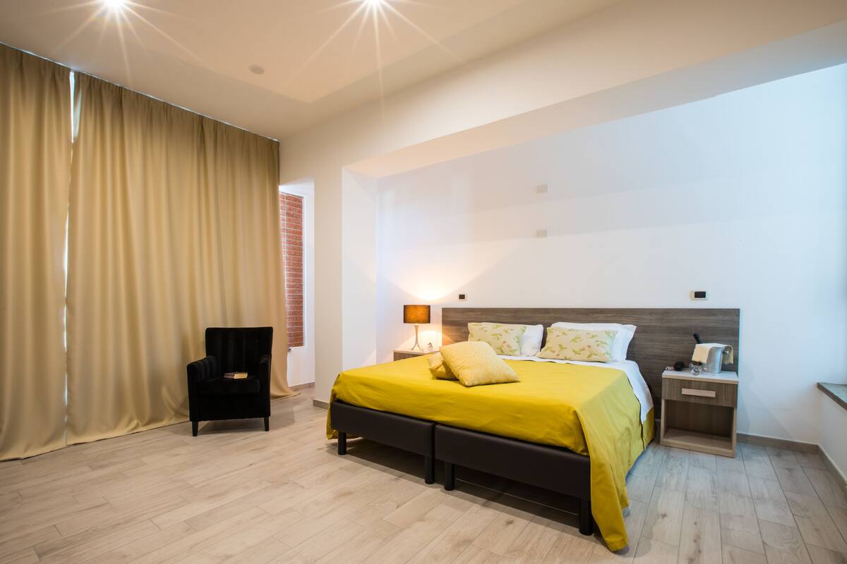 Un dormitorio moderno con una cama grande, una mesita de noche, una lámpara y una silla.