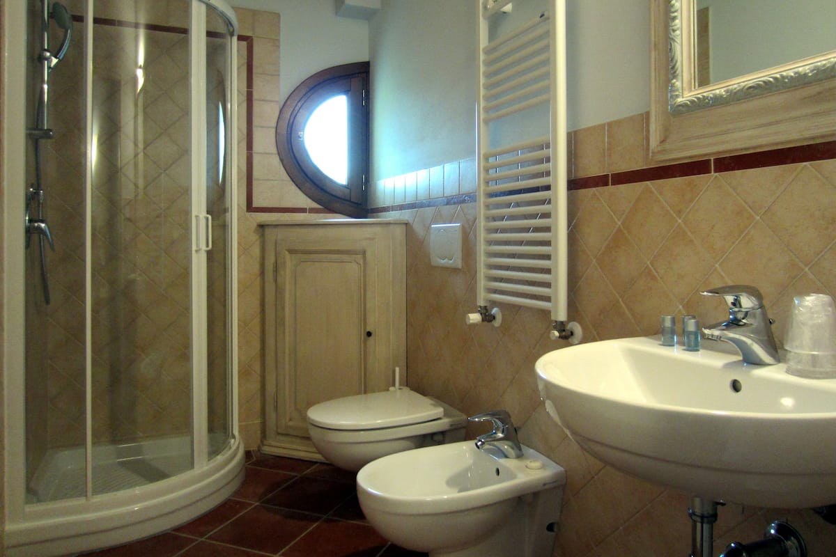 A bathroom with a glass shower enclosure, a toilet, a bidet, and a sink.