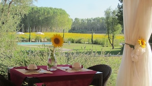 A table set outdoors with a view of a garden and a pool. - Le Colombaie Country Resort (Ponsacco)