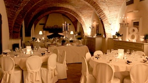 A banquet hall with white tablecloths, round tables, and chairs, featuring a brick ceiling and arched alcoves. - Le Colombaie Country Resort (Ponsacco)