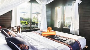 A bedroom with a bed, a chair, and a window with curtains. - Sunrise Huts Lembongan (Lembongan Island)