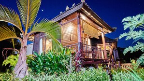 A traditional wooden building with a balcony, surrounded by lush tropical vegetation. - Sunrise Huts Lembongan (Lembongan Island)